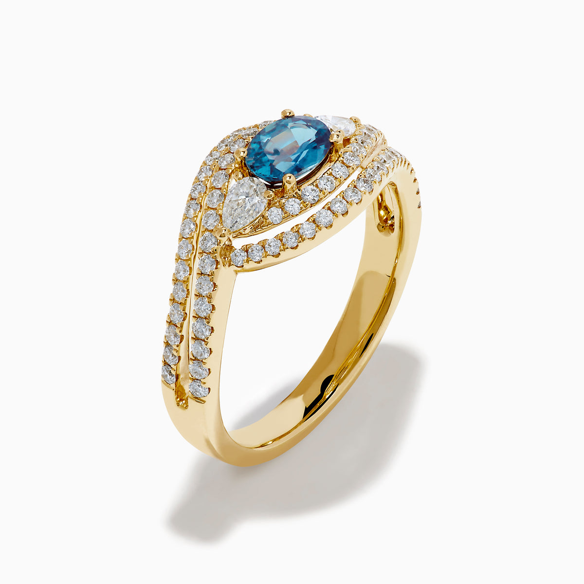 The 18K Yellow Gold Alexandrite and Diamond Swirl Halo Ring features a central oval blue alexandrite, two marquise-cut diamonds, and rows of small round diamonds in an eye-shaped swirl design.
