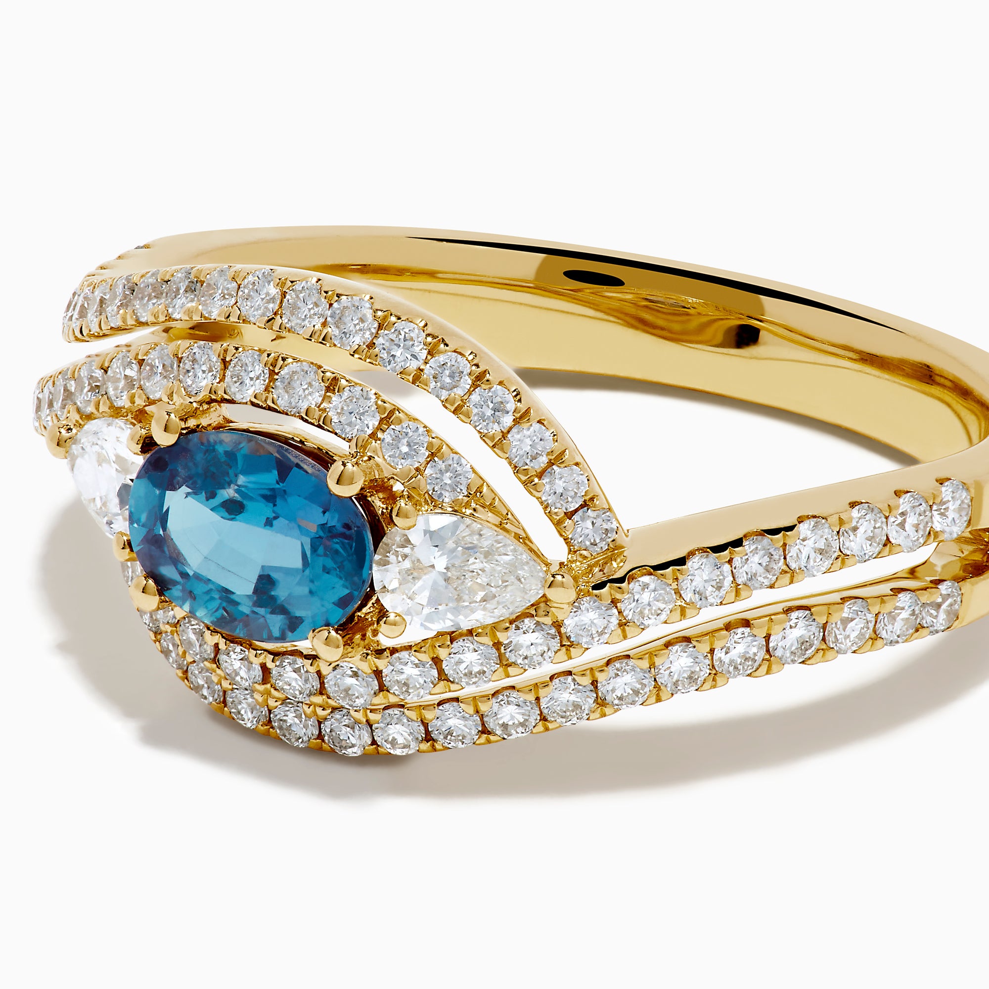 The 18K Yellow Gold Alexandrite and Diamond Swirl Halo Ring features a central oval blue alexandrite, two marquise-cut diamonds, and rows of small round diamonds in an eye-shaped swirl design.