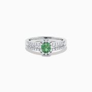 The 18K White Gold Alexandrite and Diamond Split Halo Ring showcases a central oval green Alexandrite, surrounded by a diamond halo with additional diamonds set along the band.