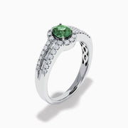 The 18K White Gold Alexandrite and Diamond Split Halo Ring showcases a central oval green Alexandrite, surrounded by a diamond halo with additional diamonds set along the band.