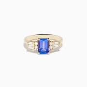 The Nahla 14K Yellow Gold Tanzanite and Diamond Ring showcases a rectangular blue tanzanite center, with two round diamonds and two baguette-cut white stones on each side, displayed on a white background.