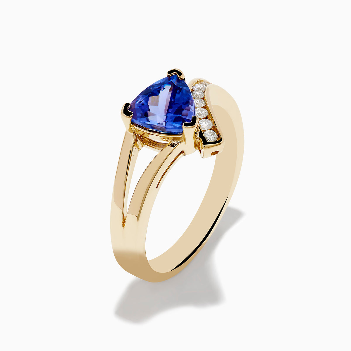 The Nahla 14K Yellow Gold Tanzanite and Diamond Ring features a triangular blue tanzanite center, accented by a curved row of sparkling round white diamonds on one side of the band.