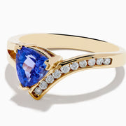 The Nahla 14K Yellow Gold Tanzanite and Diamond Ring features a triangular blue tanzanite center, accented by a curved row of sparkling round white diamonds on one side of the band.