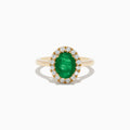 The 14K Yellow Gold Emerald and Diamond Ring features an oval green emerald center stone encircled by a halo of small round white diamonds, shown against a white background.