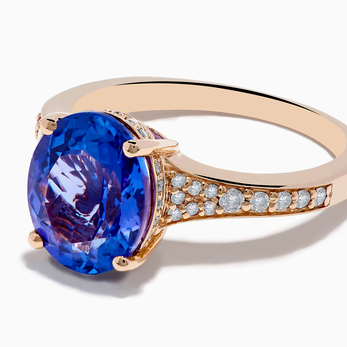 The Nahla 14K Rose Gold Tanzanite and Diamond Ring showcases an oval-cut blue tanzanite centerpiece accented by round diamonds on the band, set against a white background.