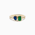The 14K Yellow Gold Emerald and Sapphire Toi Et Moi Diamond Ring features a teardrop sapphire, rectangular green emerald, and small diamonds set along half the band, shown on a white background.