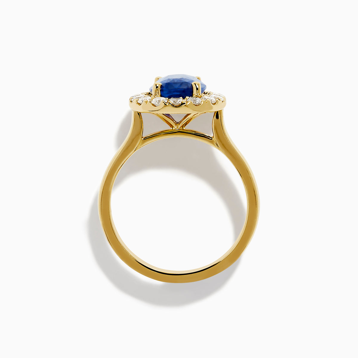 The Royale Bleu 18K Yellow Gold Blue Sapphire and Diamond Halo Ring showcases a striking oval blue sapphire centerpiece surrounded by a sparkling diamond halo.