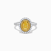 The 18K Two Tone Gold White and GIA Certified Yellow Diamond Double Halo Ring features a central oval yellow diamond, surrounded by white diamonds and additional diamonds set along the band.