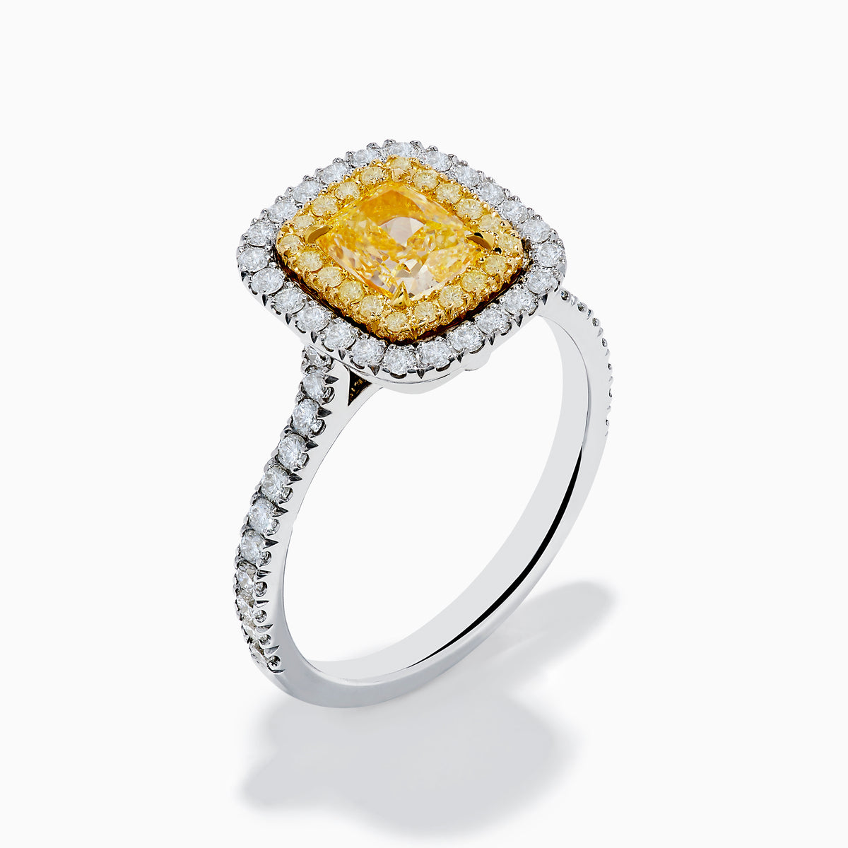 The 18K Two Toned Gold GIA certified Yellow and White Diamond Halo Ring features a rectangular yellow center stone, double halos of white diamonds, and extra diamonds along the band for exceptional brilliance.