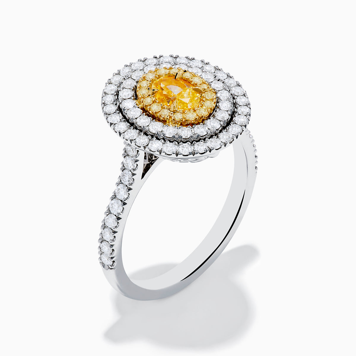 An 18K two-toned gold GIA certified Yellow and White Diamond Double Halo Ring, with an oval yellow center stone encircled by double halos of white diamonds on a diamond-accented band, displayed on a white background.