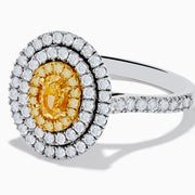An 18K two-toned gold GIA certified Yellow and White Diamond Double Halo Ring, with an oval yellow center stone encircled by double halos of white diamonds on a diamond-accented band, displayed on a white background.