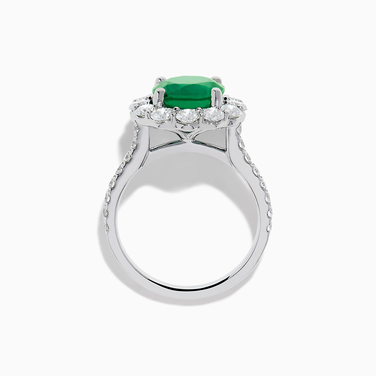 The 18K White Gold Emerald and Diamond Halo Ring features a large round green emerald center, surrounded by sparkling diamonds on the halo and band, beautifully displayed on a white background.