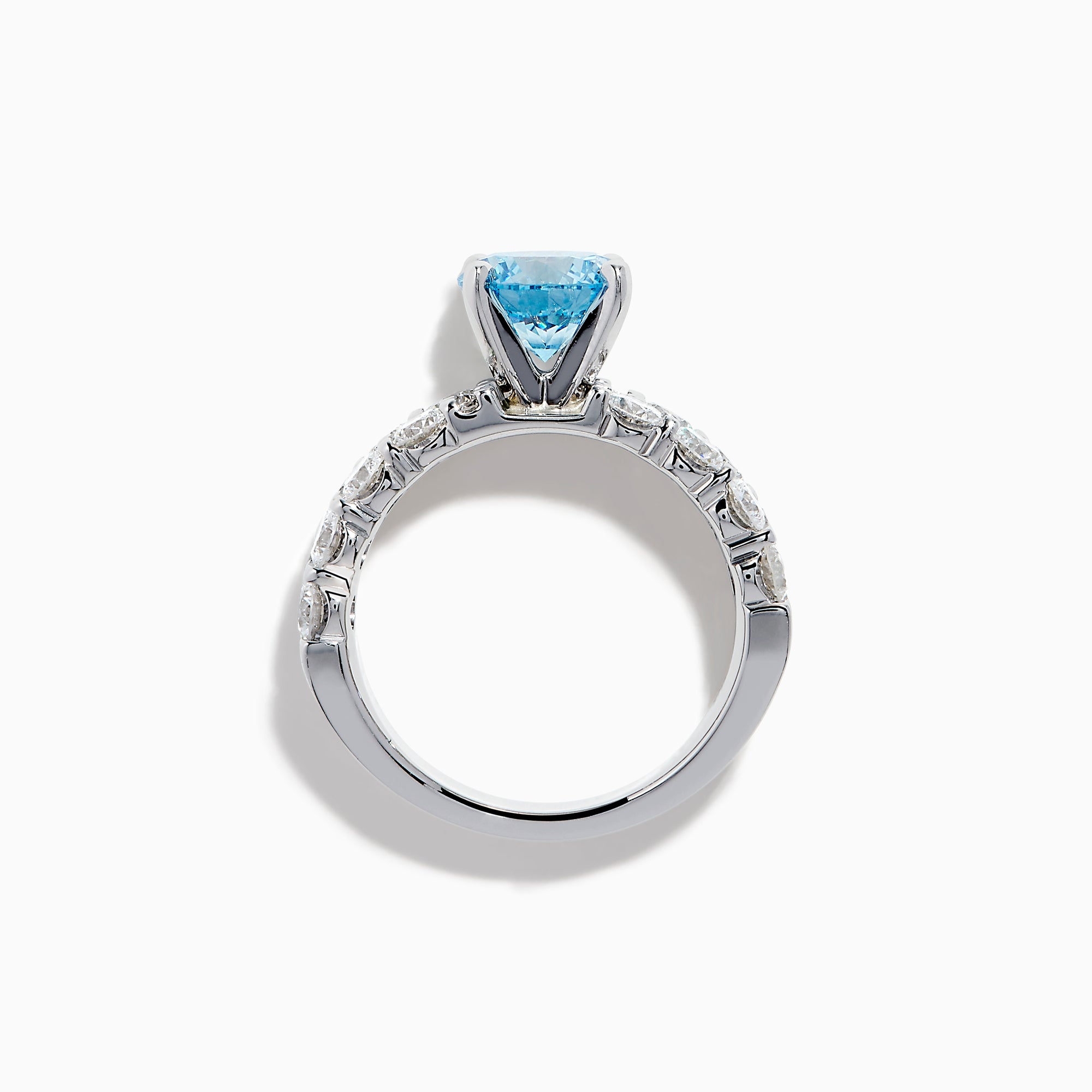 The Lab Grown Blue Diamond Round Brilliant Solitaire Ring in 14K White Gold features a striking round blue diamond center, accented by two rows of sparkling clear diamonds along the band, shown on a white background.