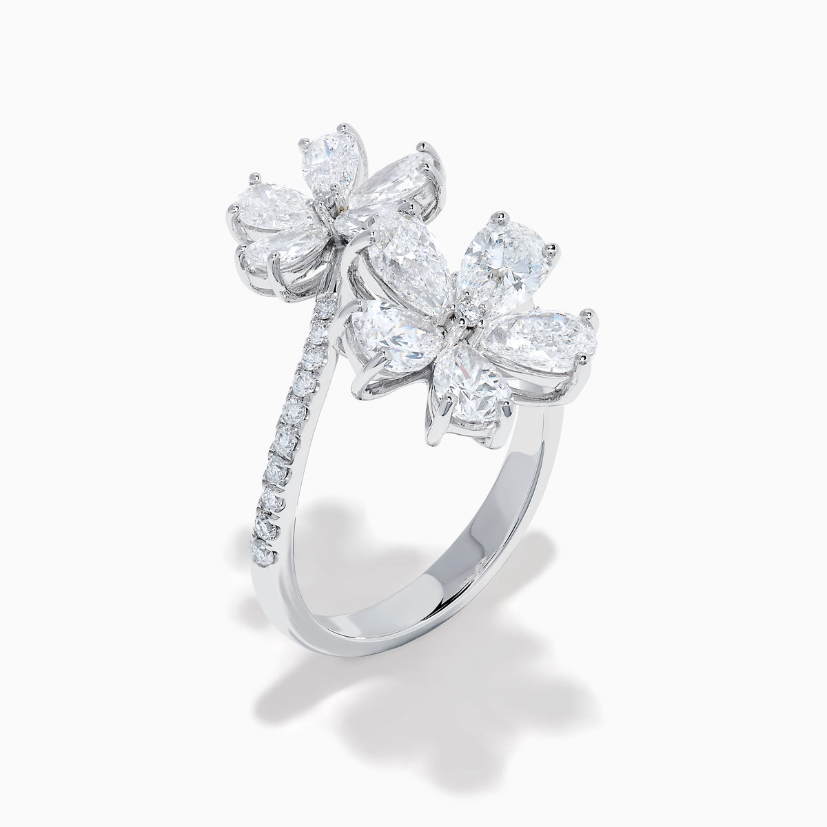The Lab Grown Pear and Round Diamond 2.75ct Flower Bypass Ring in 14K White Gold features two flower designs with pear-shaped and round diamonds on a partially encrusted band, set against a white background for an elegant look.