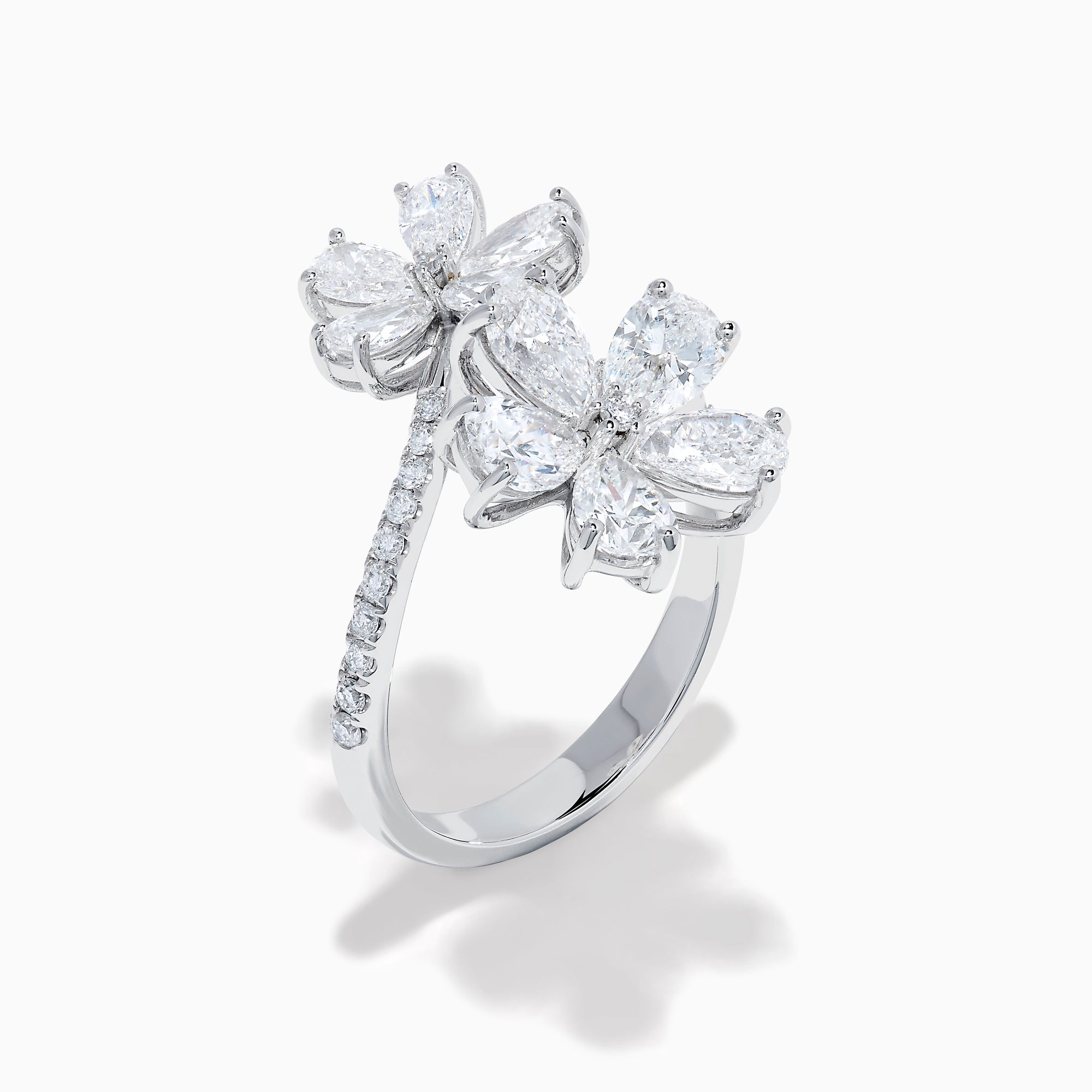 The Lab Grown Pear and Round Diamond 2.75ct Flower Bypass Ring in 14K White Gold features two flower designs with pear-shaped and round diamonds on a partially encrusted band, set against a white background for an elegant look.