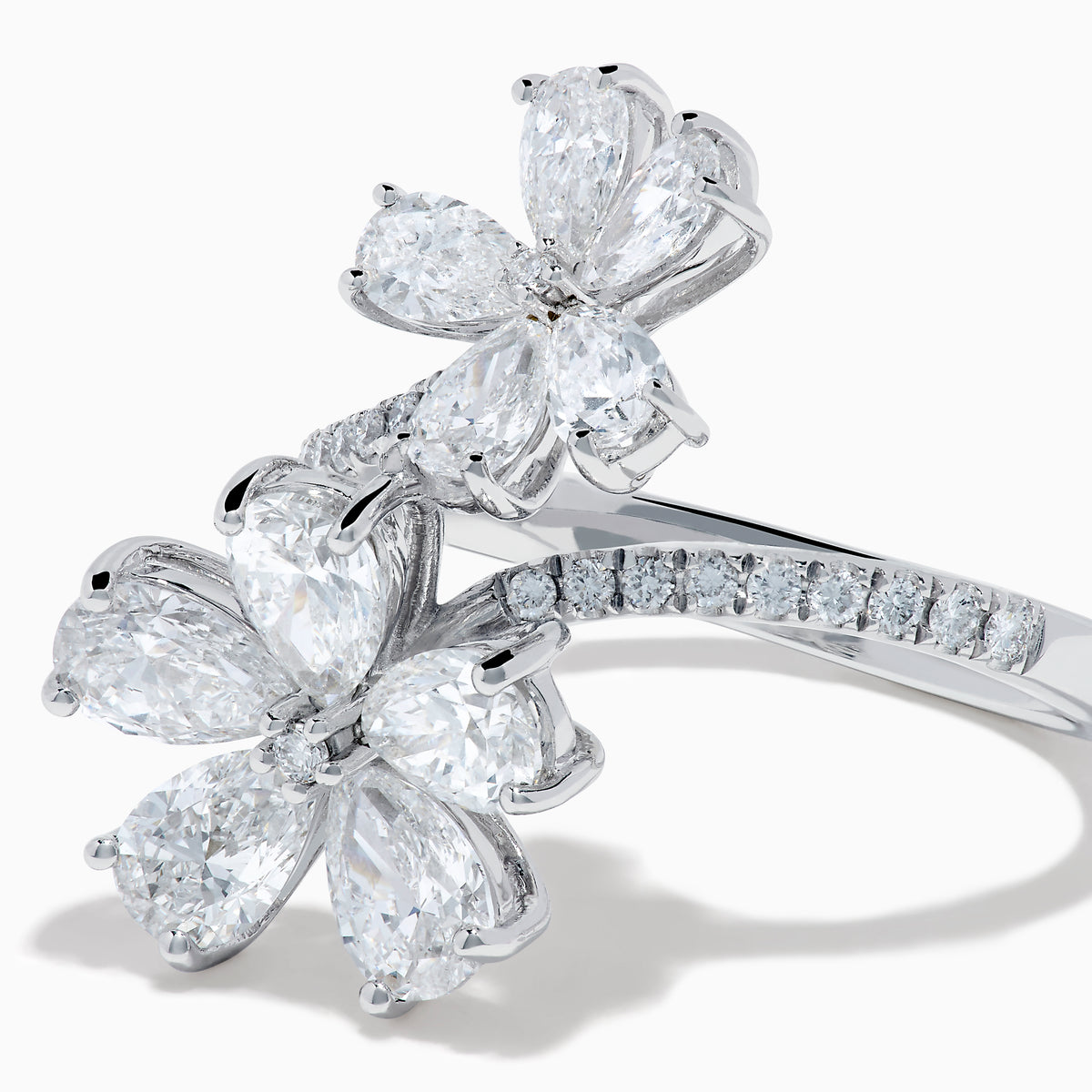 The Lab Grown Pear and Round Diamond 2.75ct Flower Bypass Ring in 14K White Gold features two flower designs with pear-shaped and round diamonds on a partially encrusted band, set against a white background for an elegant look.