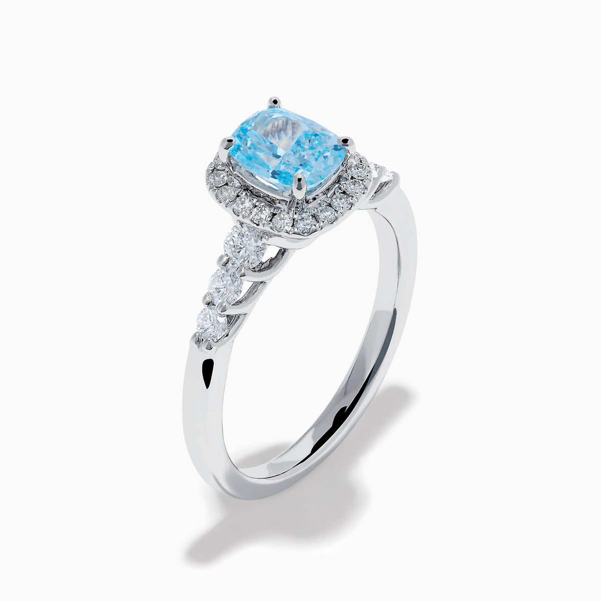 The Lab Grown Blue and White Diamond Halo Ring in 14K White Gold showcases a rectangular light blue center stone, surrounded by lab grown diamonds and accented with diamonds along the band for added sparkle.