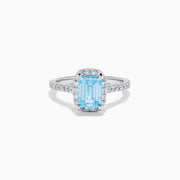 The Lab Grown Blue and White Diamond Halo Ring in 14K White Gold features an emerald-cut blue center stone with lab grown diamond accents, beautifully showcased on a white background.
