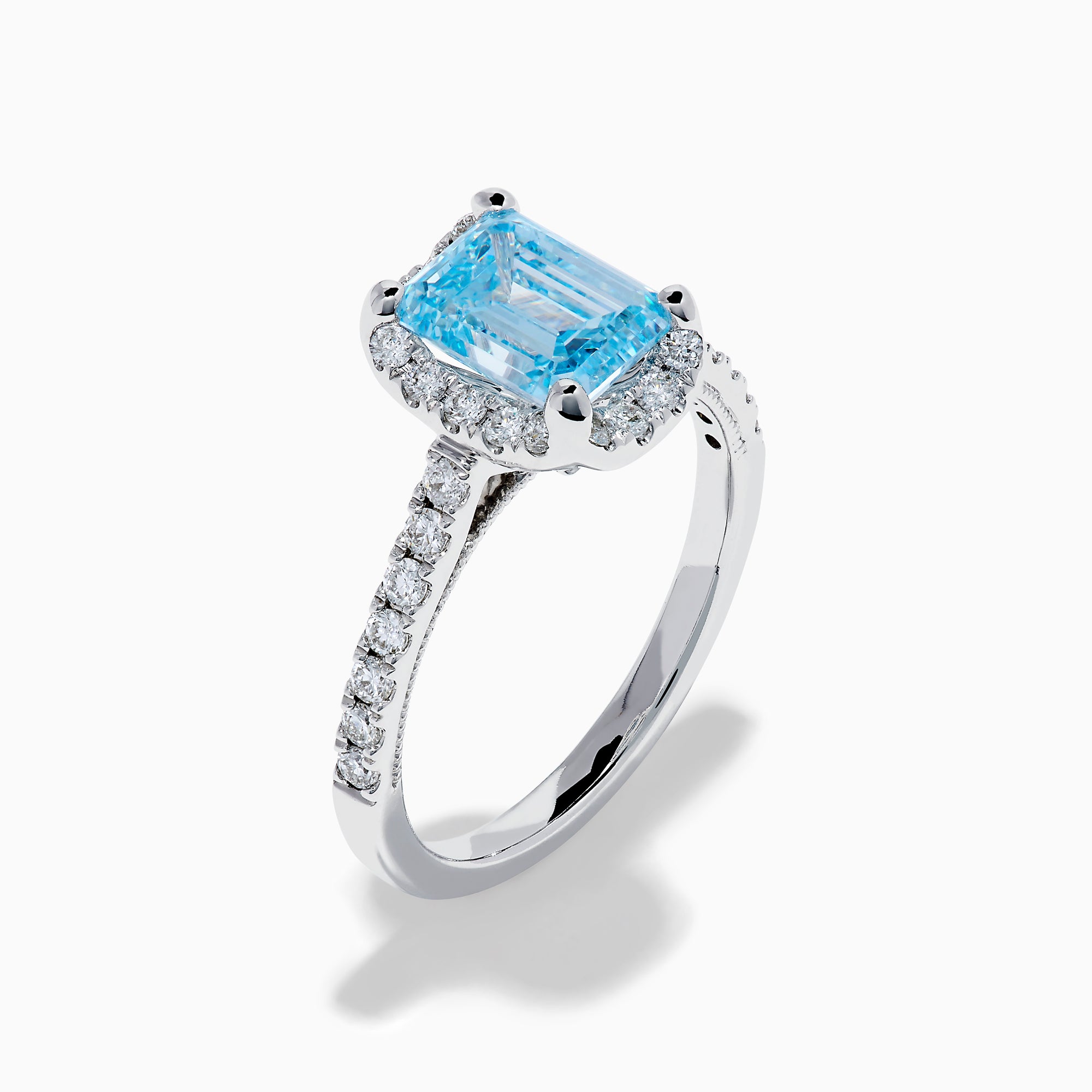 The Lab Grown Blue and White Diamond Halo Ring in 14K White Gold features an emerald-cut blue center stone with lab grown diamond accents, beautifully showcased on a white background.