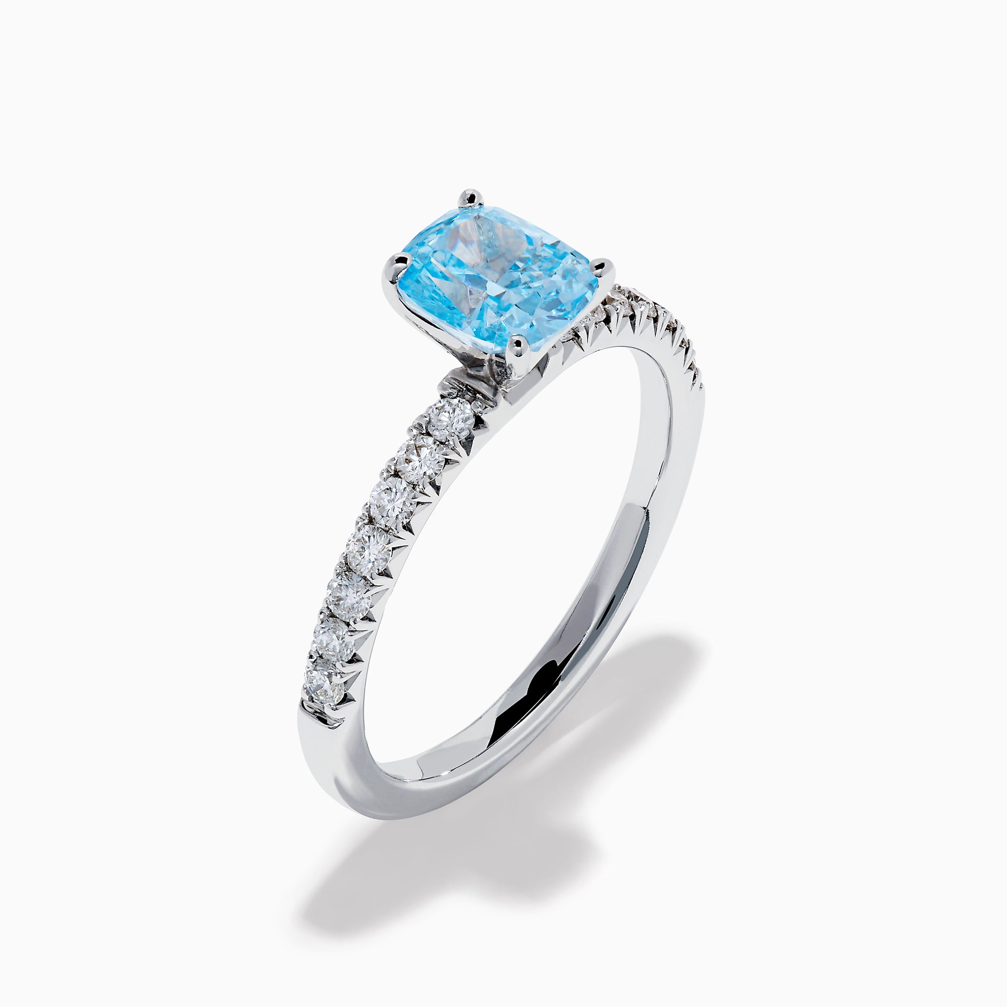 The Lab Grown Blue Diamond Solitaire Cushion Ring in 14K White Gold features a rectangular lab grown blue diamond at the center, accented with small clear round stones along the band.