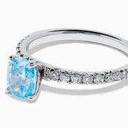 The Lab Grown Blue Diamond Solitaire Cushion Ring in 14K White Gold features a rectangular lab grown blue diamond at the center, accented with small clear round stones along the band.