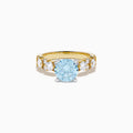 The Lab Grown Blue and White Diamond Ring in 14K Yellow Gold showcases a large round light blue gemstone at the center, accented by three teardrop-shaped lab grown white diamonds on each side.