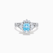 The Lab Grown Blue and White Diamond Ring in 14K White Gold showcases an oval blue gemstone surrounded by a halo of lab grown diamonds, with more diamonds accenting the band.