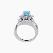 The Lab Grown Blue and White Diamond Ring in 14K White Gold showcases an oval blue gemstone surrounded by a halo of lab grown diamonds, with more diamonds accenting the band.