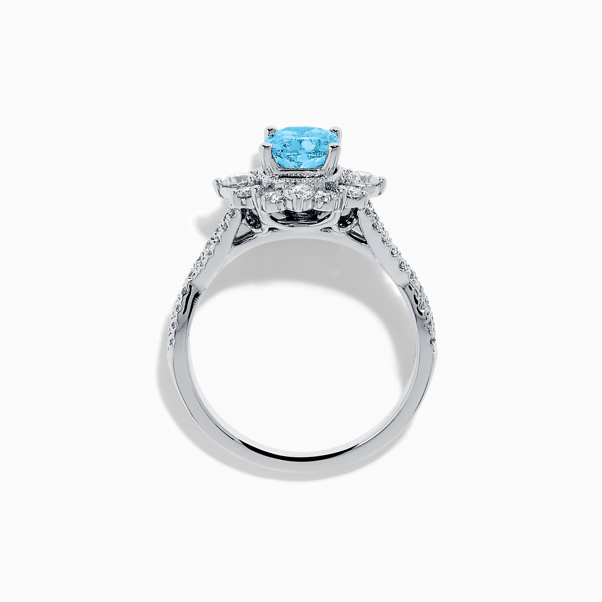 The Lab Grown Blue and White Diamond Ring in 14K White Gold showcases an oval blue gemstone surrounded by a halo of lab grown diamonds, with more diamonds accenting the band.