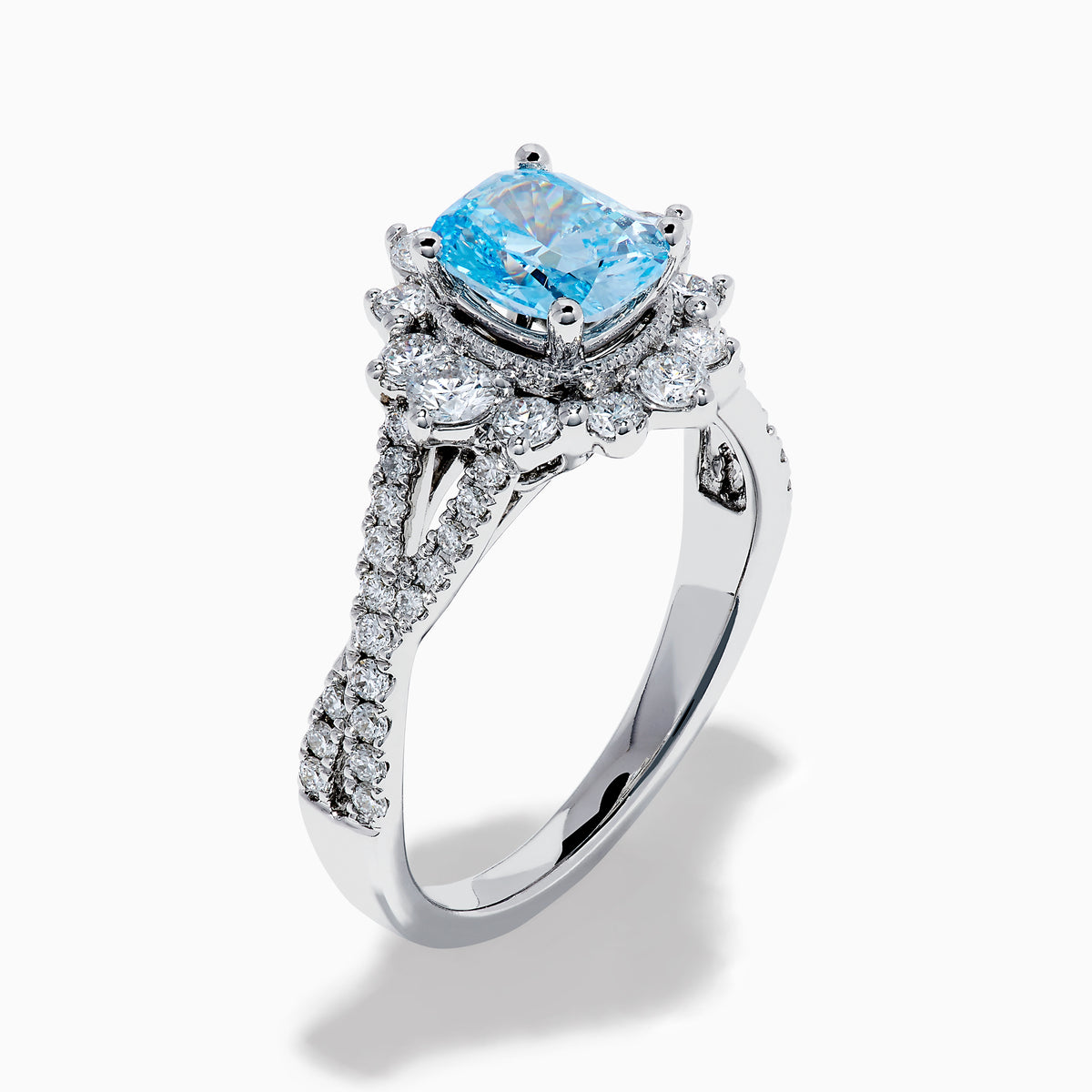 The Lab Grown Blue and White Diamond Ring in 14K White Gold showcases an oval blue gemstone surrounded by a halo of lab grown diamonds, with more diamonds accenting the band.