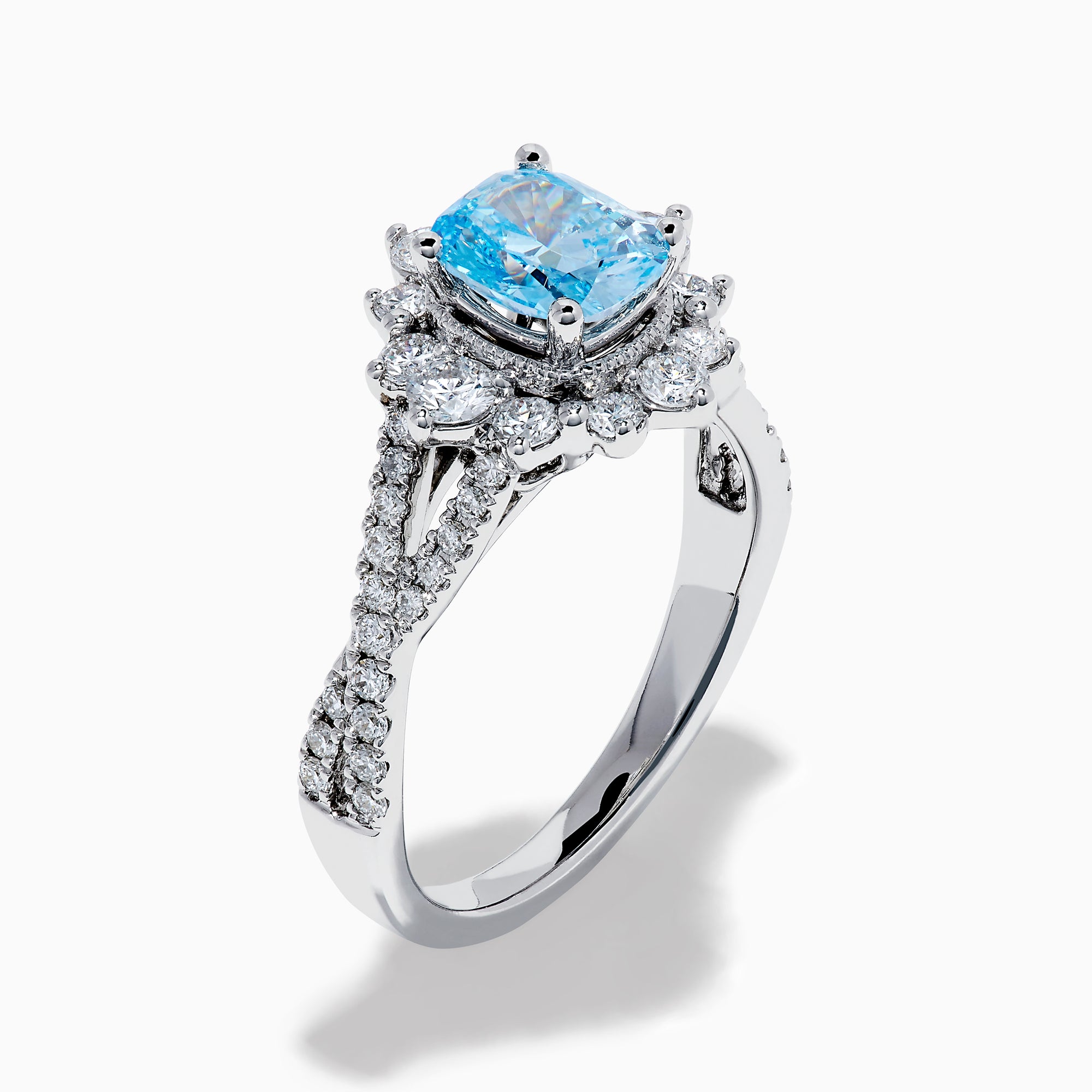 The Lab Grown Blue and White Diamond Ring in 14K White Gold showcases an oval blue gemstone surrounded by a halo of lab grown diamonds, with more diamonds accenting the band.
