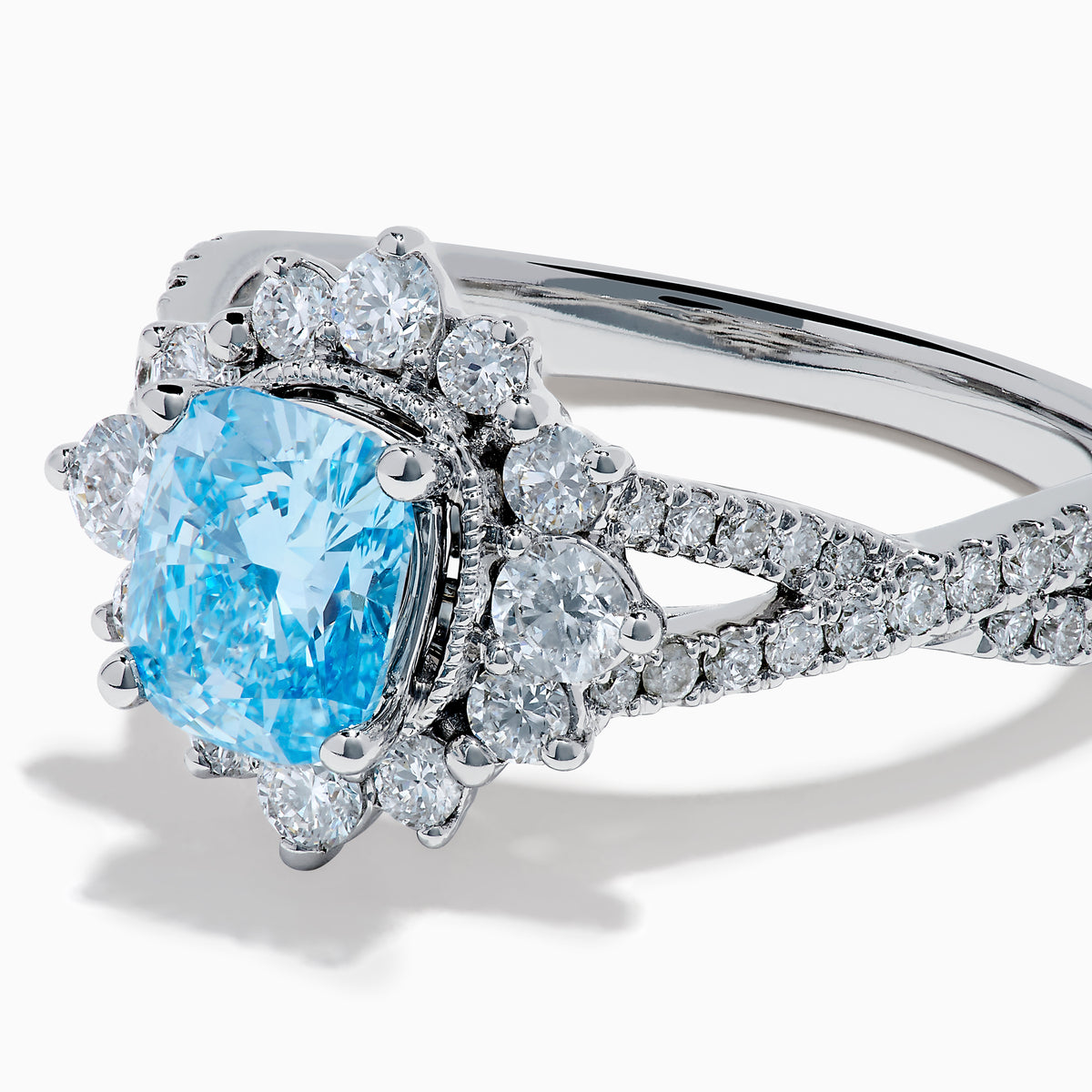 The Lab Grown Blue and White Diamond Ring in 14K White Gold showcases an oval blue gemstone surrounded by a halo of lab grown diamonds, with more diamonds accenting the band.