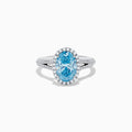 The 14K White Gold Lab Grown Blue and White Diamond Ring showcases an oval blue center stone, a halo of blue and white diamonds, and extra diamonds along the band for stunning brilliance.