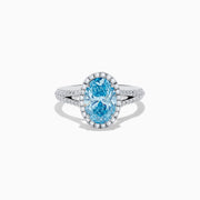 The 14K White Gold Lab Grown Blue and White Diamond Ring showcases an oval blue center stone, a halo of blue and white diamonds, and extra diamonds along the band for stunning brilliance.
