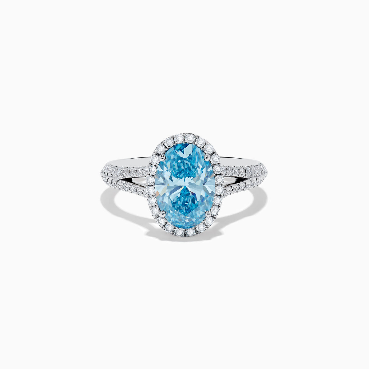 The 14K White Gold Lab Grown Blue and White Diamond Ring showcases an oval blue center stone, a halo of blue and white diamonds, and extra diamonds along the band for stunning brilliance.