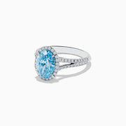 The 14K White Gold Lab Grown Blue and White Diamond Ring showcases an oval blue center stone, a halo of blue and white diamonds, and extra diamonds along the band for stunning brilliance.