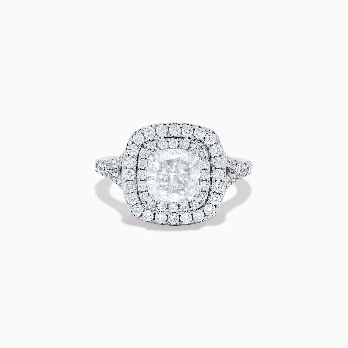 The Lab Grown Cushion Diamond Double Halo Ring in 14K White Gold features a cushion-cut center diamond, double halo of smaller diamonds, and additional diamonds along the band.