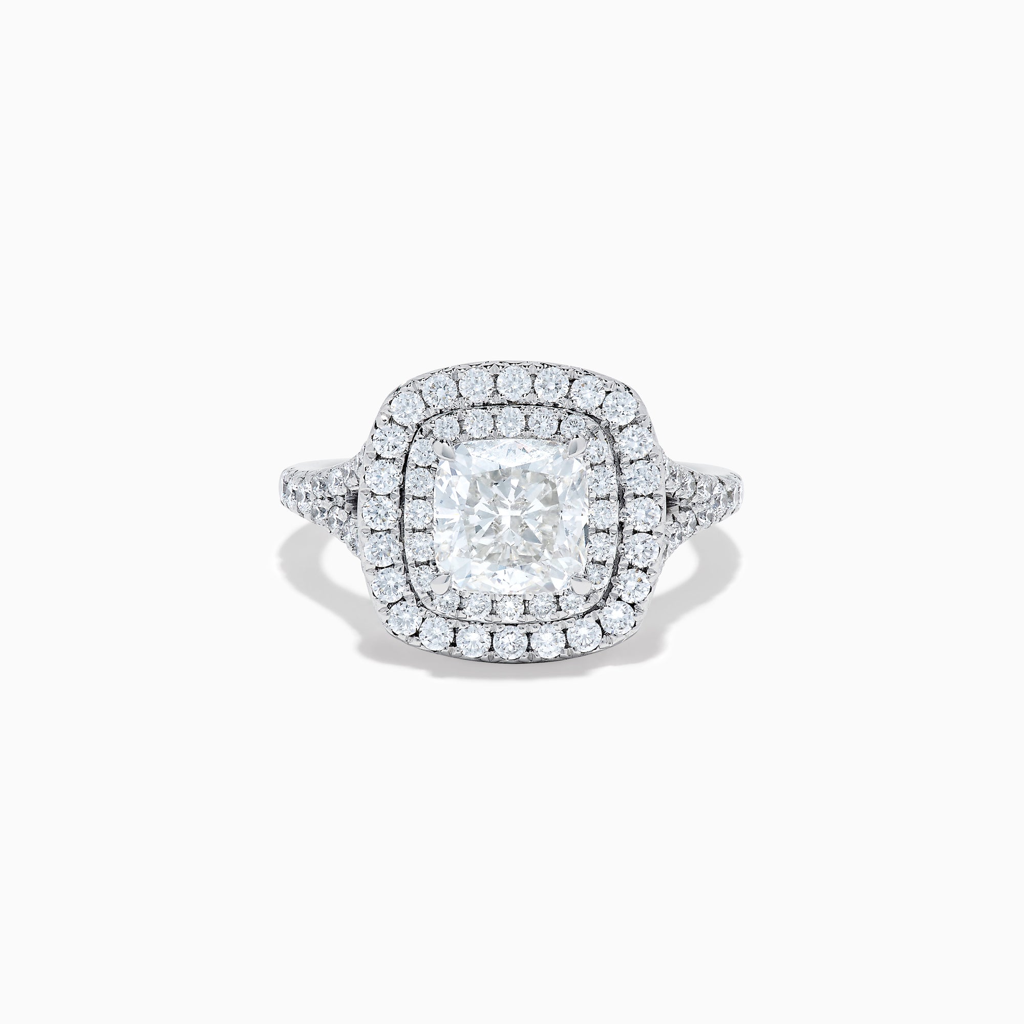 The Lab Grown Cushion Diamond Double Halo Ring in 14K White Gold features a cushion-cut center diamond, double halo of smaller diamonds, and additional diamonds along the band.