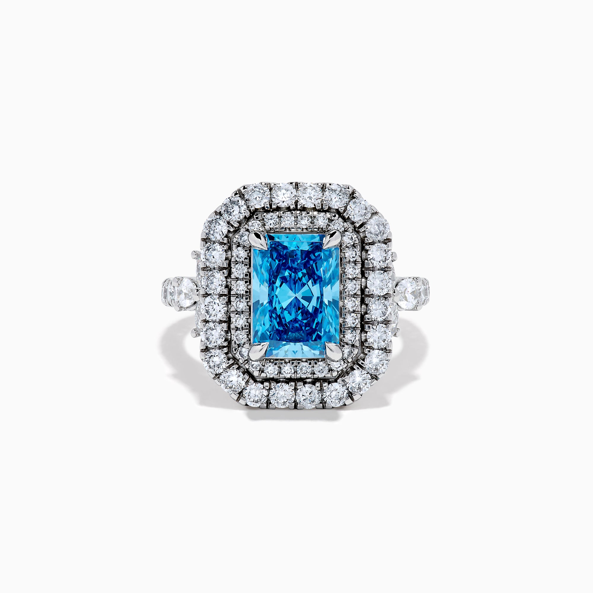 The Lab Grown Blue Diamond Double Halo Cocktail Ring in 14K White Gold features a rectangular blue center, round white diamonds on the band, and is displayed against a white background.