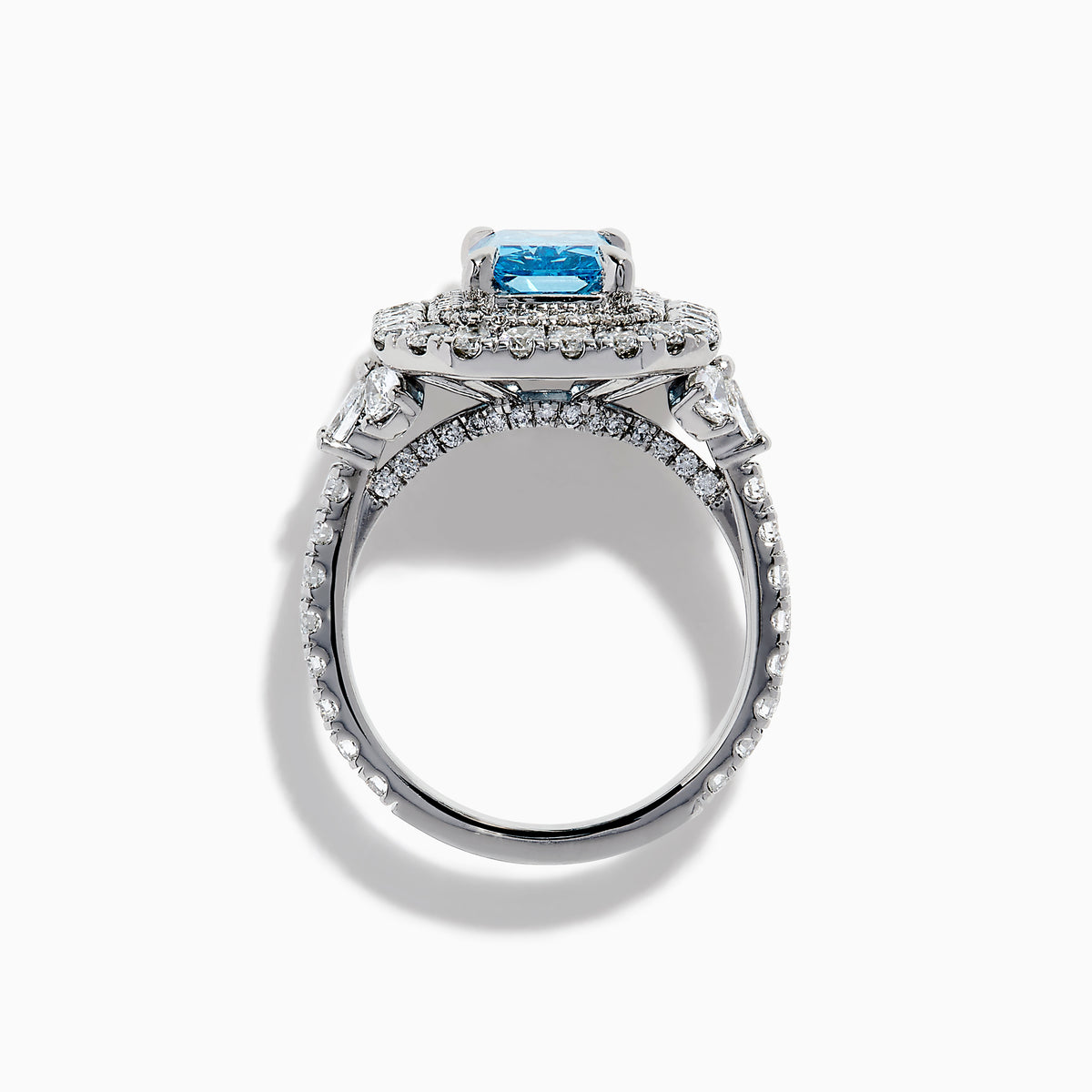 The Lab Grown Blue Diamond Double Halo Cocktail Ring in 14K White Gold features a rectangular blue center, round white diamonds on the band, and is displayed against a white background.