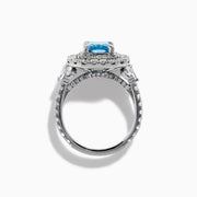 The Lab Grown Blue Diamond Double Halo Cocktail Ring in 14K White Gold features a rectangular blue center, round white diamonds on the band, and is displayed against a white background.