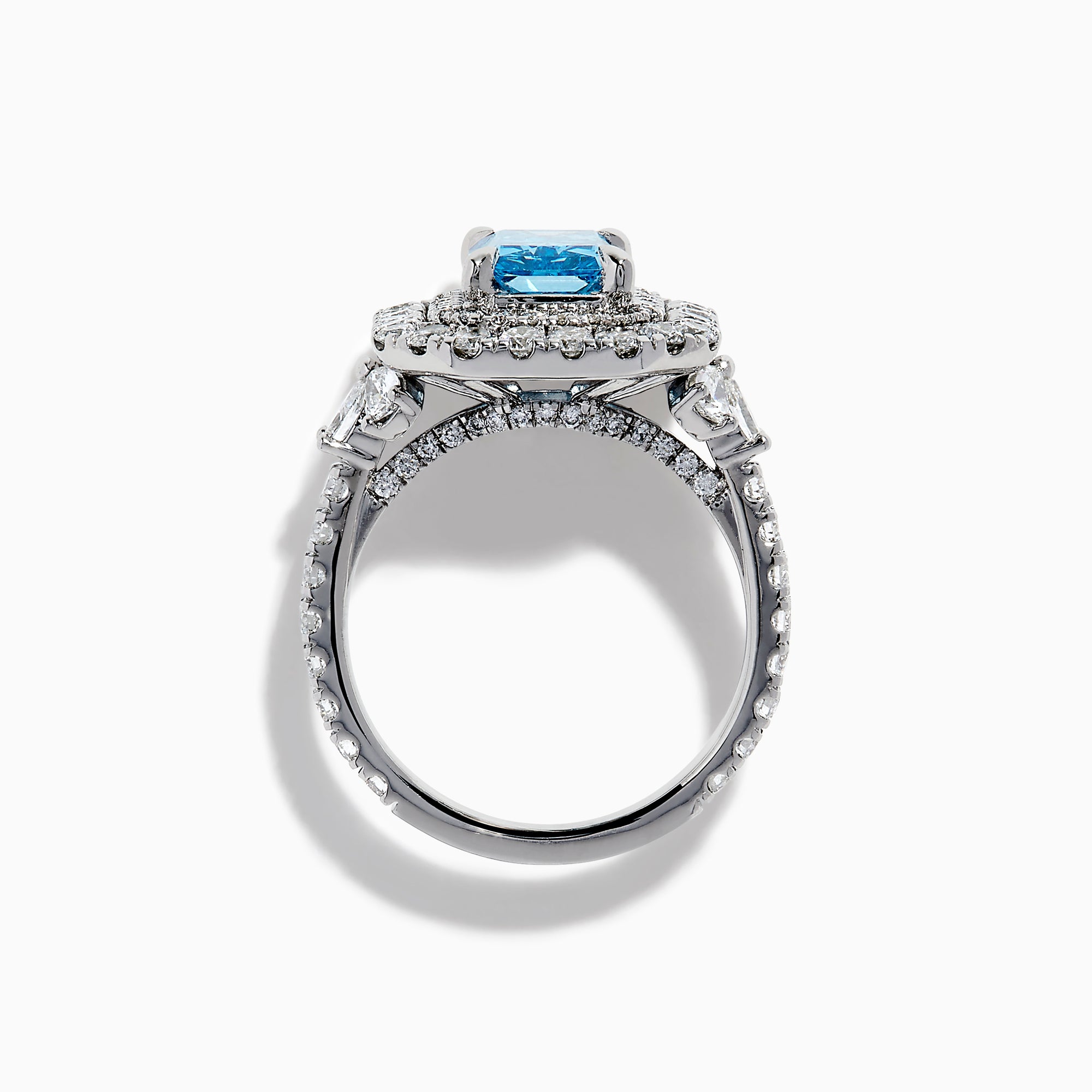 The Lab Grown Blue Diamond Double Halo Cocktail Ring in 14K White Gold features a rectangular blue center, round white diamonds on the band, and is displayed against a white background.