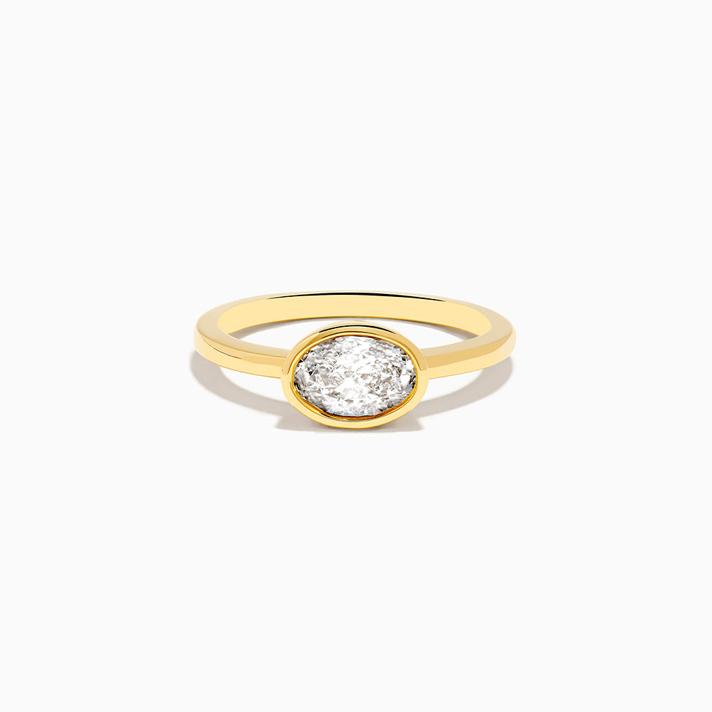 The Lab Grown Diamond East West Oval Ring in 14K Yellow Gold showcases a single lab diamond in a sleek bezel setting, presented against a plain white background.