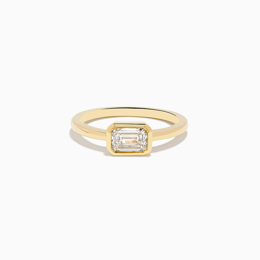 The Lab Grown Diamond East West Emerald-Cut Ring in 14K Yellow Gold features a lab diamond in a minimalist bezel setting, beautifully crafted and shown against a plain white background.