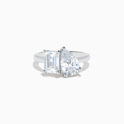 The Lab Grown Diamond Toi Et Moi Ring in 14K White Gold showcases emerald-cut and pear-shaped lab diamonds set side by side on a sleek band, displayed against a white background.