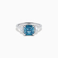 Lab Grown Blue and White Diamond 3-Stone Ring in 14K White Gold, featuring a prominent cushion-cut blue and white diamond center with two clear triangular side stones, shown on a white background.