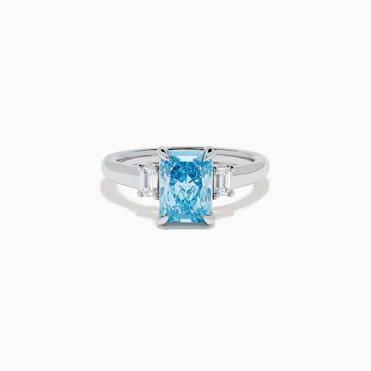 The Lab Grown Blue Diamond 3-Stone Ring in 14K White Gold features a brilliant blue center diamond with two clear rectangular side stones, set in sleek white gold against a crisp white background.