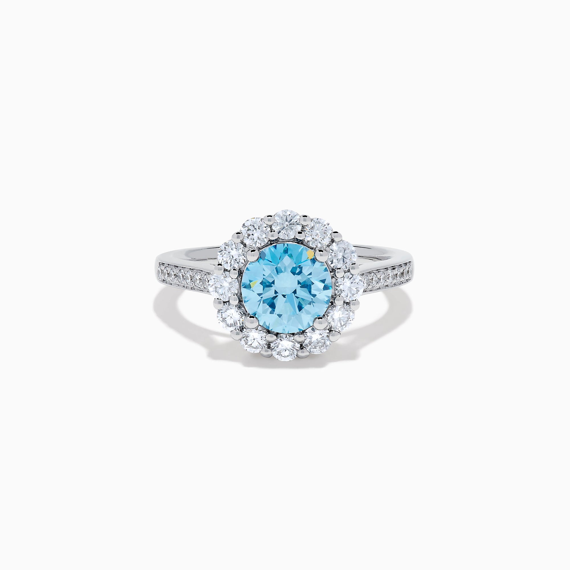 The Lab Grown Blue and White Diamond Halo Ring in 14K White Gold showcases a striking round blue center stone, encircled by lab grown diamond accents and additional diamonds adorning the band.