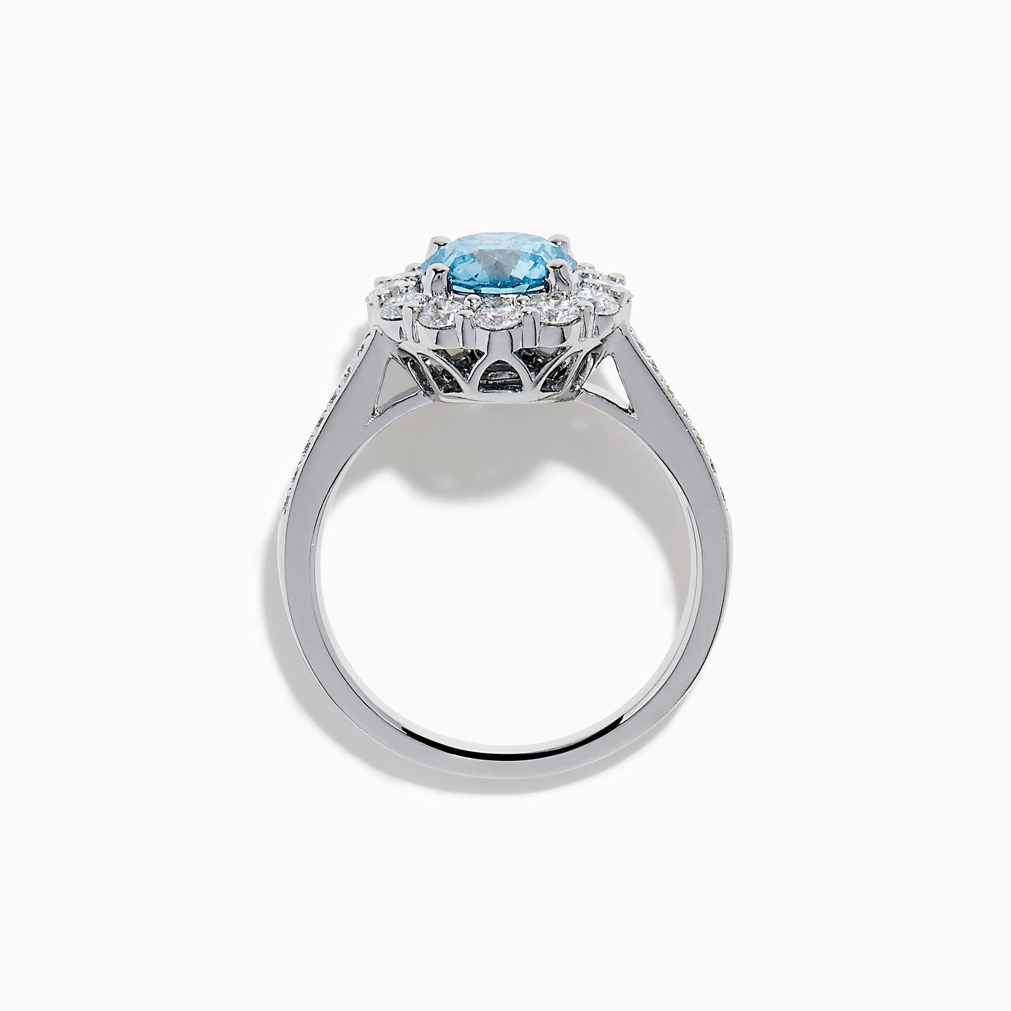 The Lab Grown Blue and White Diamond Halo Ring in 14K White Gold showcases a striking round blue center stone, encircled by lab grown diamond accents and additional diamonds adorning the band.
