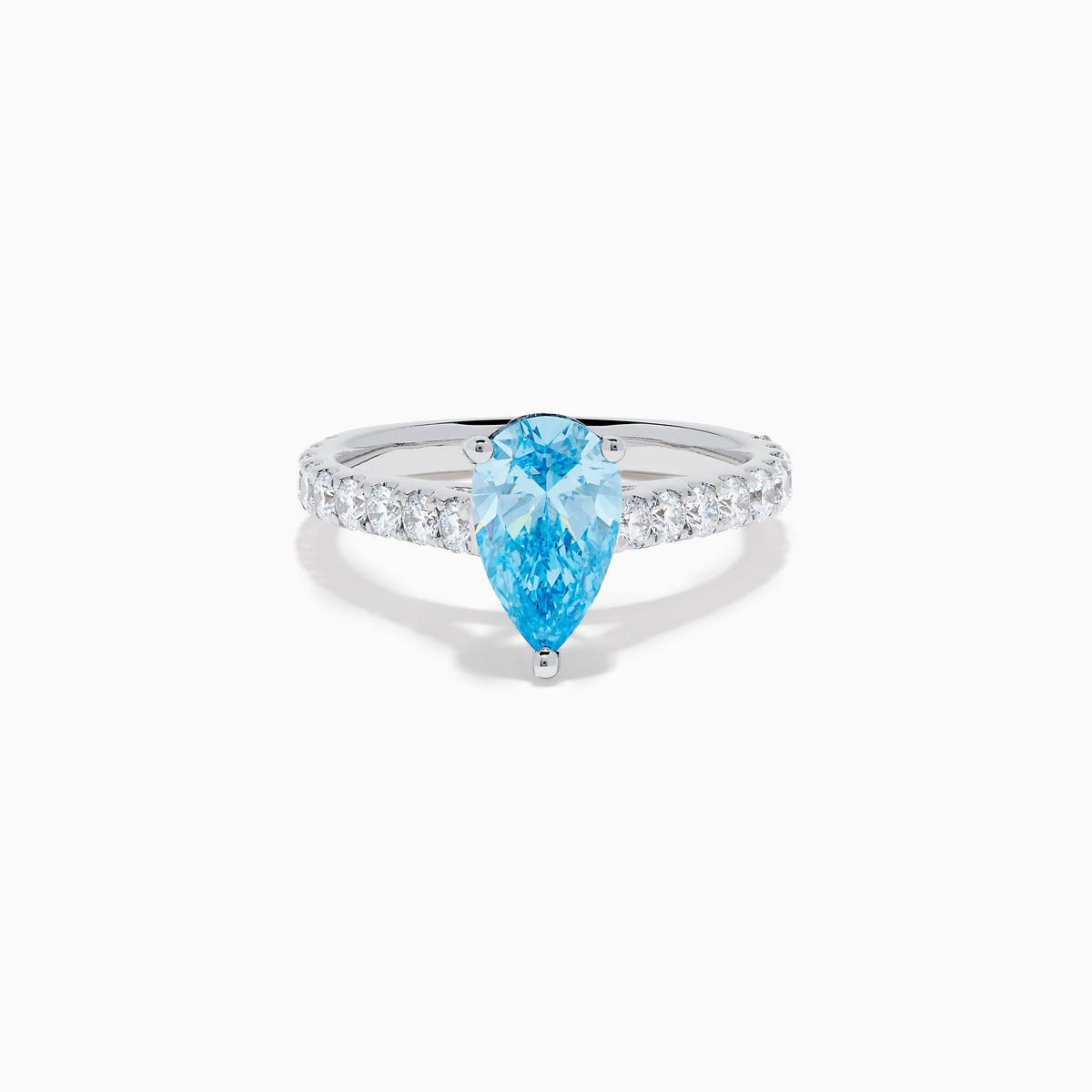 The Lab Grown Blue Diamond Solitaire Pear Ring in 14K White Gold features a striking pear-shaped blue diamond at the center, accented by a band adorned with small round white diamonds.